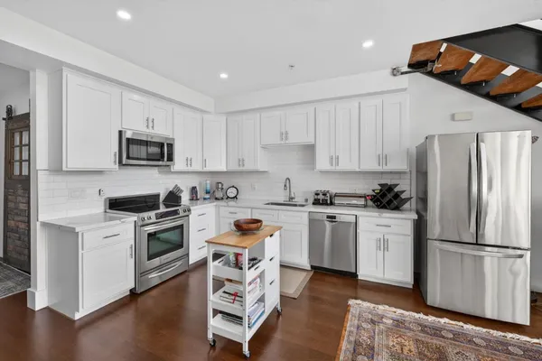 a kitchen with granite countertop a refrigerator stove top oven and sink