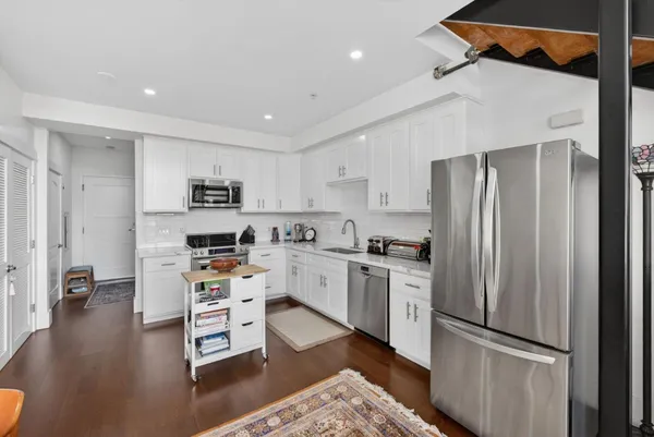 a kitchen with stainless steel appliances a refrigerator a stove a sink dishwasher and a refrigerator with wooden floor