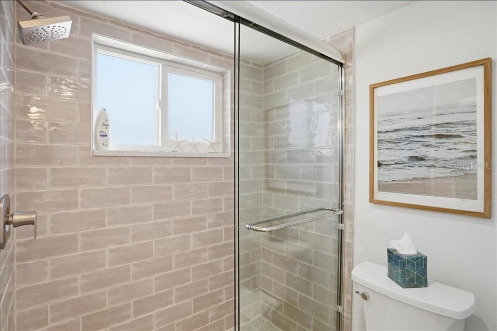 8911 Blind Pass Road, Unit 118 St. Pete Beach, FL 33706 - Photo 22 of 34 a bathroom with a shower and a toilet
