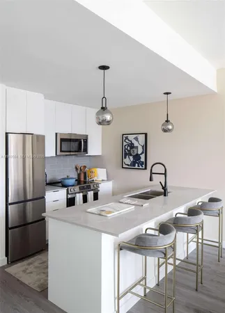 a kitchen with stainless steel appliances granite countertop a dining table chairs refrigerator and sink