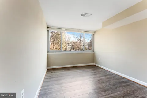 an empty room with wooden floor and window