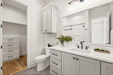 a bathroom with a granite countertop sink mirror vanity and toilet