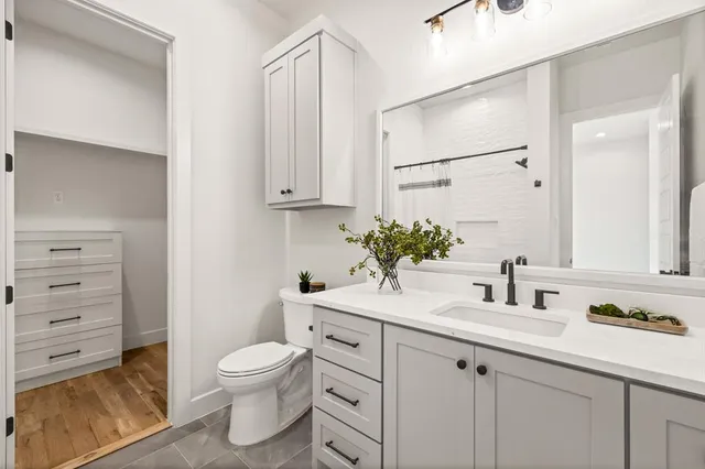 a bathroom with a granite countertop sink mirror vanity and toilet