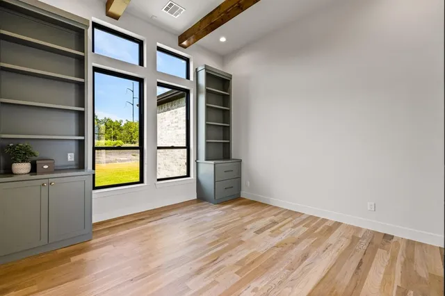 a view of an empty room with a window and wooden floor