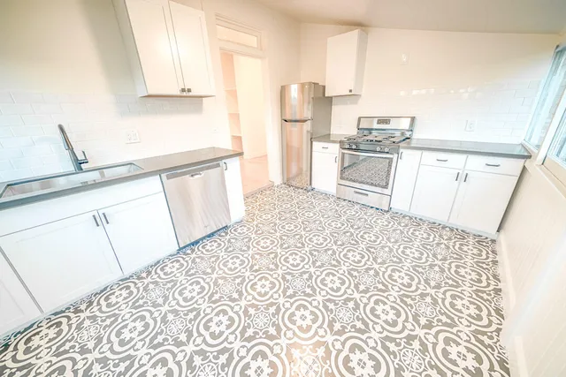 a kitchen with white cabinets and sink