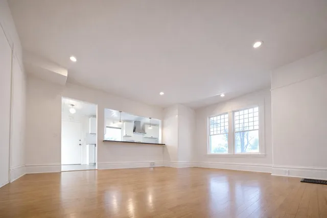 a view of an empty room with wooden floor and a window