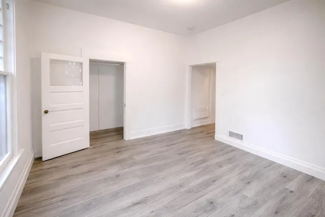an empty room with wooden floor & closet area