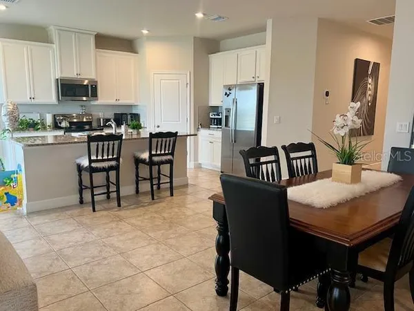a kitchen with stainless steel appliances kitchen island granite countertop a table chairs and a refrigerator