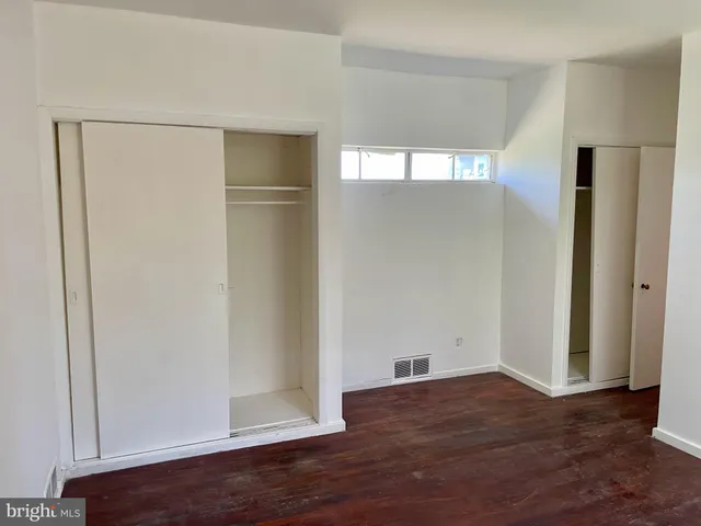 a view of empty room with wooden floor and window