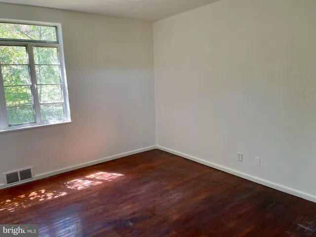 an empty room with wooden floor and windows in it