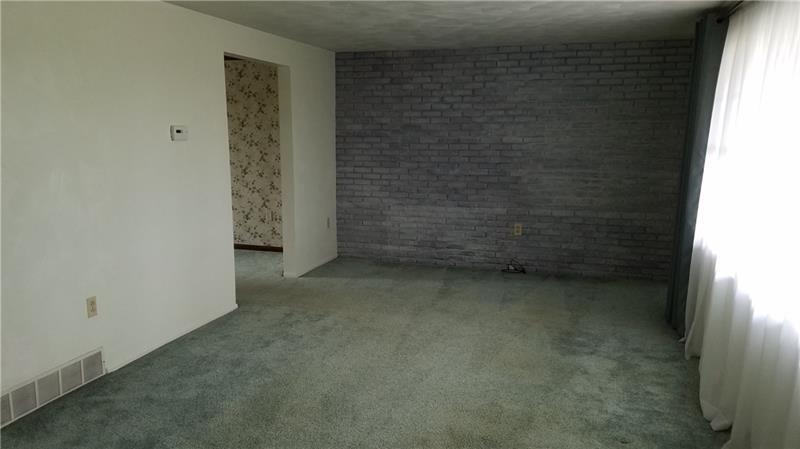 999 Hurst Road Greensburg, PA 15601 - Photo 7 of 21 Large living room with grey brick accent wall. Hardwood under carpeting