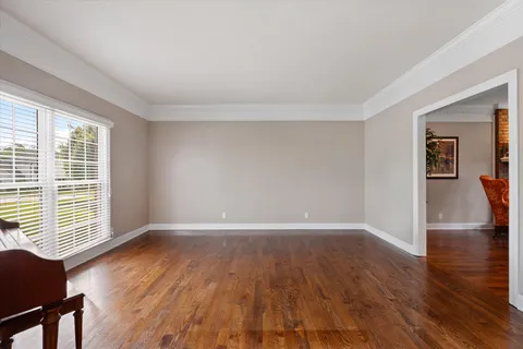 a dining room with wooden floor a chandelier a wooden table and chairs