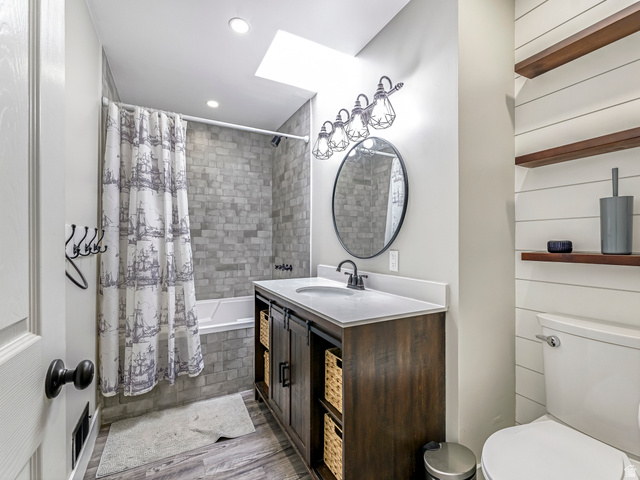 523 South Main Street Payson, UT 84651 - Photo 23 of 41 Full bathroom featuring a rectangular tub with subway tile surround, a dark wood-finish vanity with a white countertop, wood-finish flooring, and a skylight