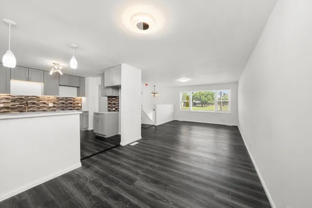 a view of an empty room and a kitchen