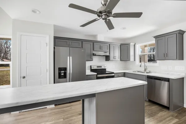 a kitchen with stainless steel appliances a sink a stove a refrigerator cabinets and wooden floor