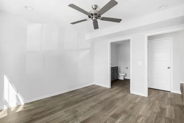 an empty room with wooden floor and a ceiling fan