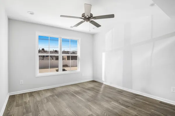 a view of an empty room with a window and wooden floor