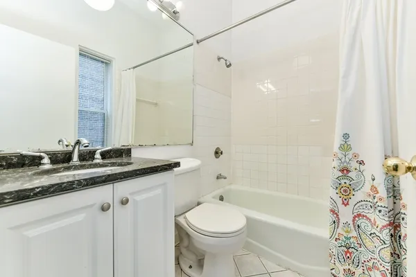 a bathroom with a granite countertop sink a toilet a mirror a bathtub and shower