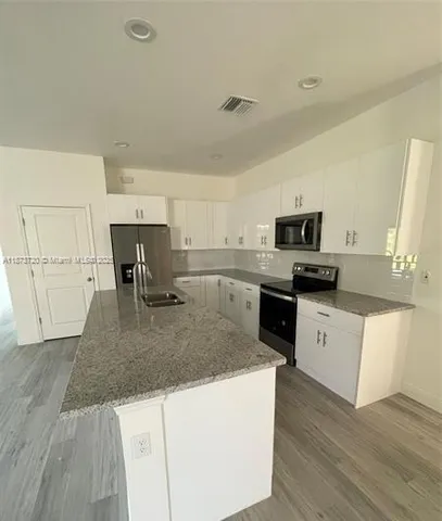 a large kitchen with stainless steel appliances granite countertop a stove a sink and a refrigerator