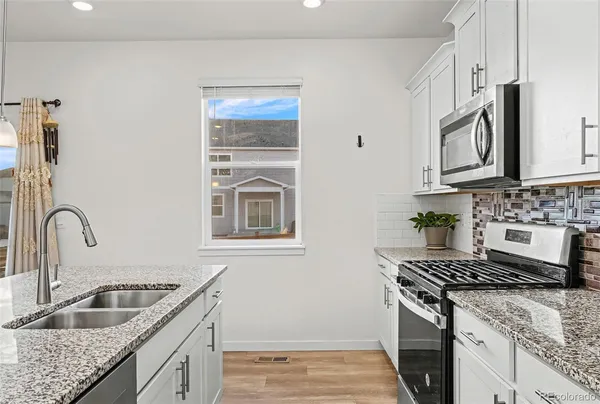 a kitchen with stainless steel appliances granite countertop a sink stove and microwave