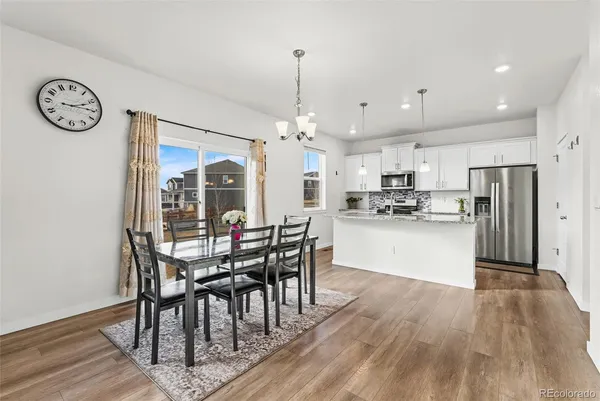 a view of a dining room and livingroom with furniture wooden floor a chandelier