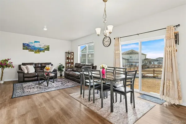 a view of a dining room and livingroom with furniture wooden floor a chandelier