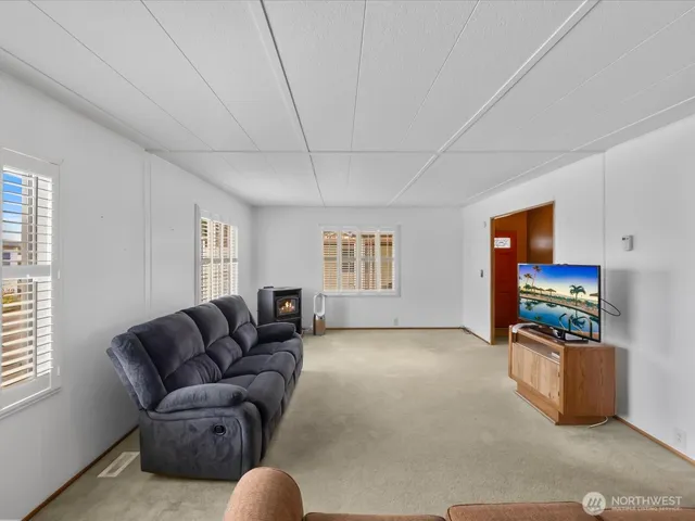 a living room with furniture a flat screen tv and a refrigerator