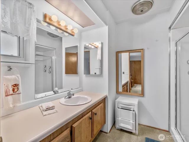 a spacious bathroom with a granite countertop double vanity sink a mirror and a shower