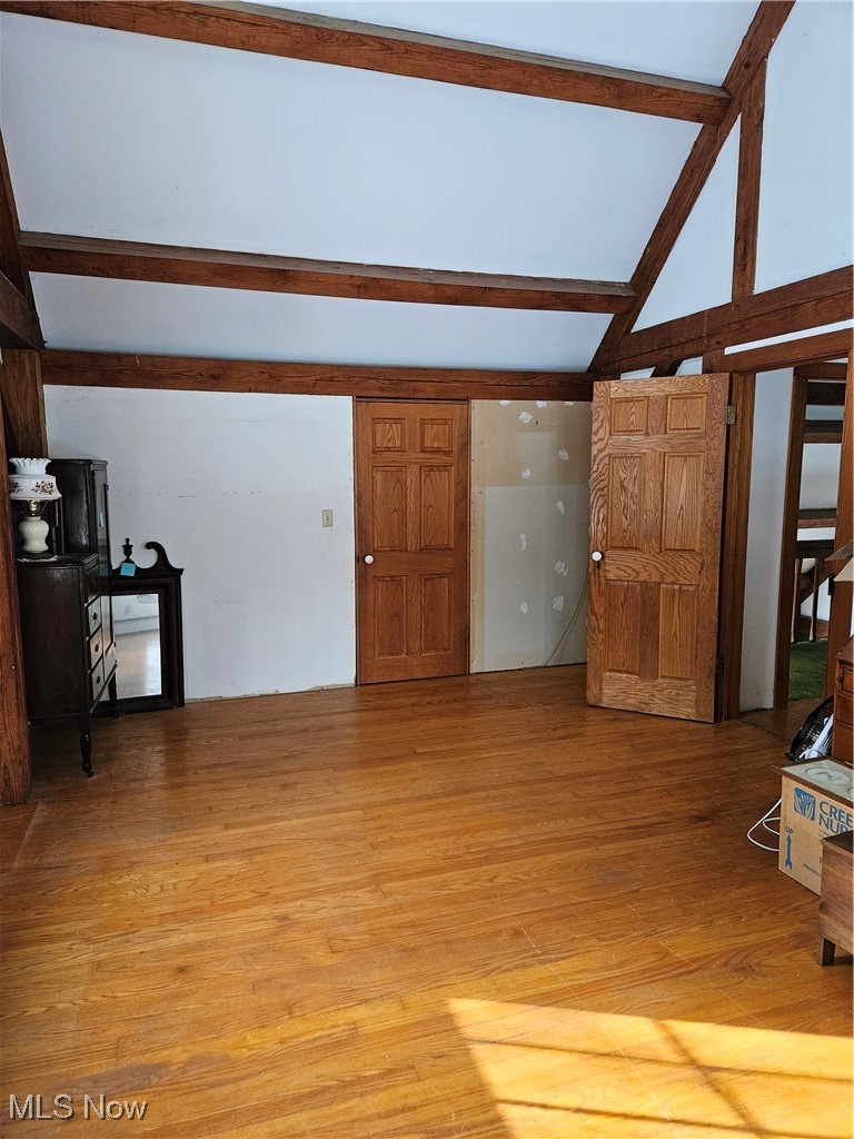 6042 Ford Road Madison, OH 44057 - Photo 13 of 25 Bedroom room featuring beam ceiling, light wood-style flooring, and high vaulted ceiling