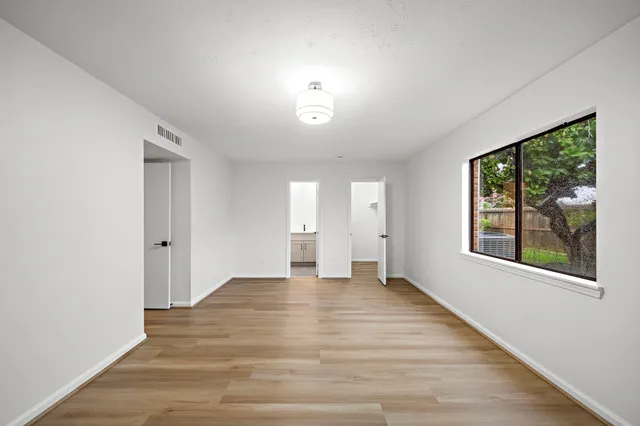 a view of an empty room with wooden floor and a window