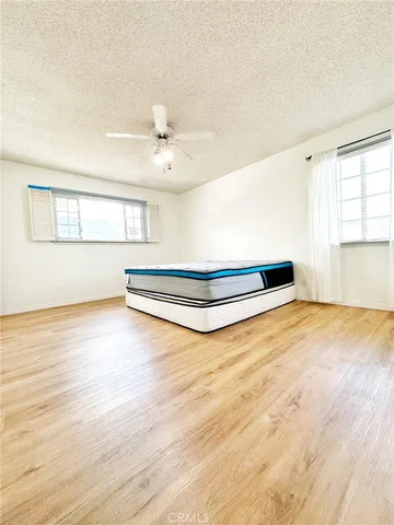 a view of a room with wooden floor ceiling fan and windows