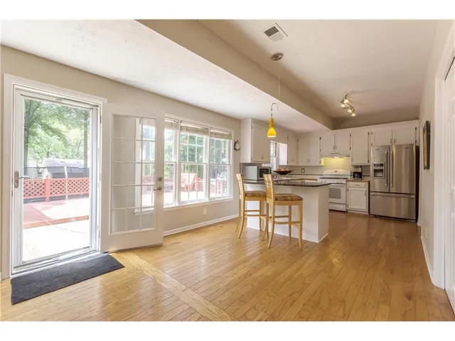 a kitchen with granite countertop white cabinets a sink a window and stainless steel appliances
