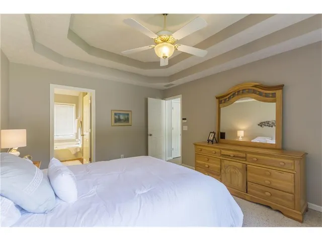 a spacious bedroom with a bed a dresser and next to a window