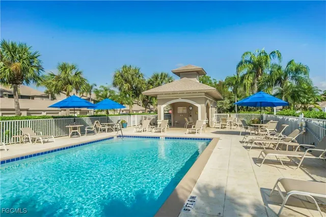 a view of a swimming pool with a table and chairs under an umbrella