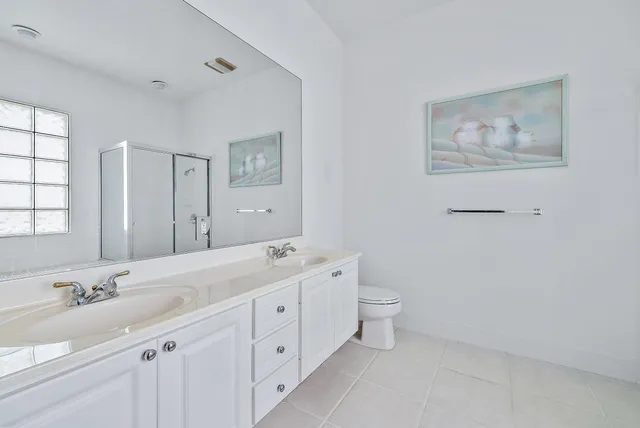 a spacious bathroom with a double vanity sink a toilet and a mirror