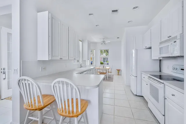 a kitchen with stainless steel appliances granite countertop a sink a stove a dining table and chairs