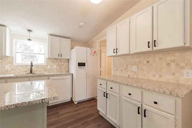 a kitchen with granite countertop white cabinets white appliances and granite counter tops