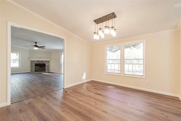 an empty room with wooden floor chandelier and fireplace