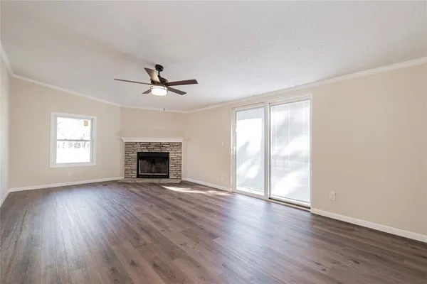 an empty room with wooden floor a ceiling fan and windows