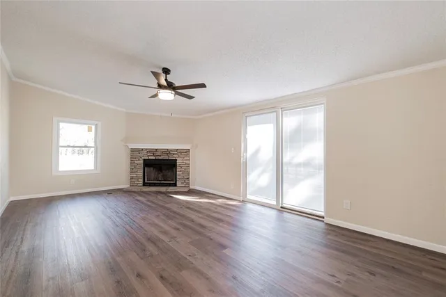 an empty room with wooden floor a ceiling fan and windows