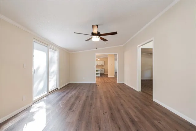 an empty room with wooden floor chandelier fan and windows
