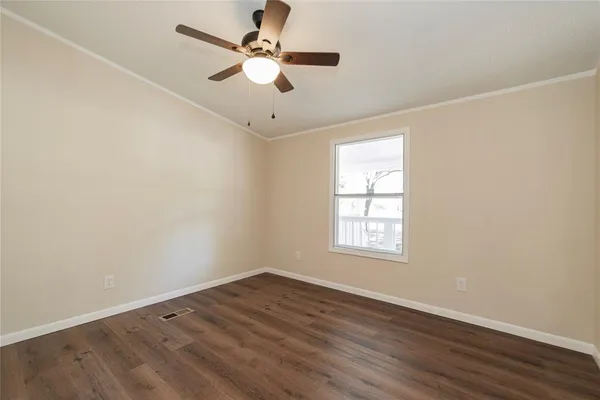 an empty room with wooden floor fan and windows