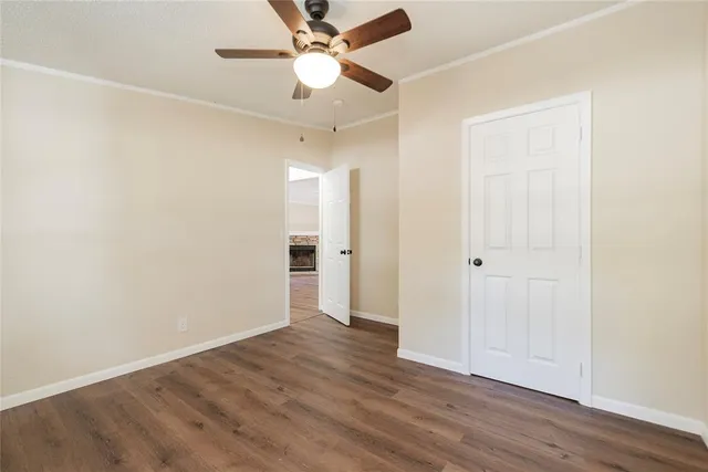 an empty room with wooden floor and ceiling fan