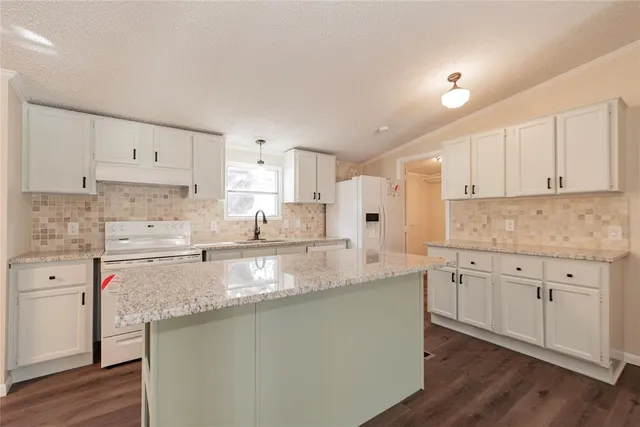 a kitchen with granite countertop white cabinets and white stainless steel appliances
