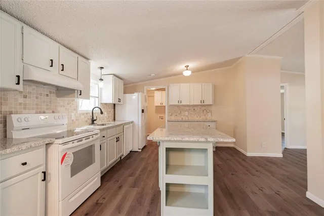 a kitchen with granite countertop white cabinets and white appliances