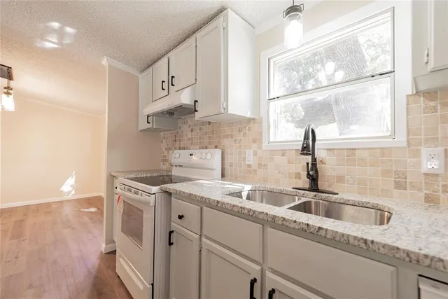 a kitchen with stainless steel appliances granite countertop a sink stove and cabinets