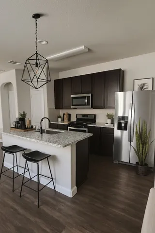 a kitchen with a refrigerator a microwave a stove and white cabinets with wooden floor