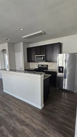 a kitchen with granite countertop a refrigerator and a stove top oven
