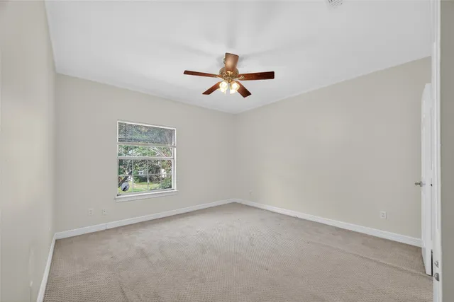 an empty room with chandelier fan and windows