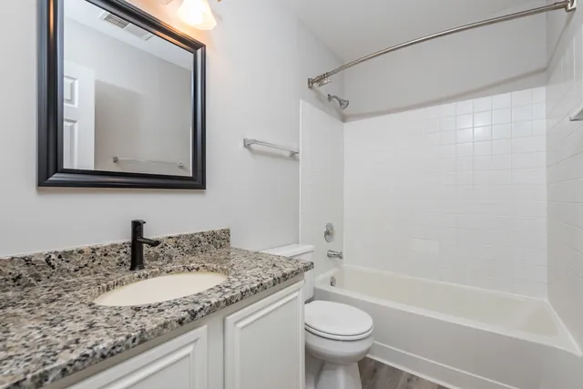 a bathroom with a granite countertop sink toilet and shower